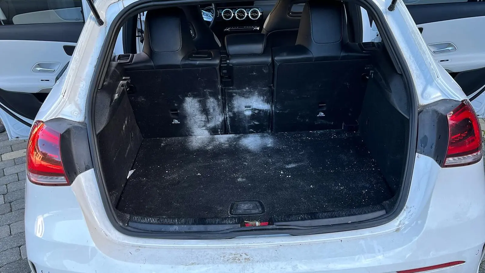Coffre de Mercedes avant nettoyage, moquette sale et taches blanches